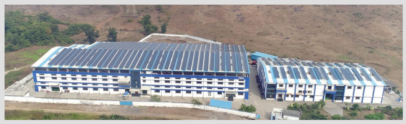 Vista aérea de la planta de Palghar: dos naves alargadas en azul y blanco, con paneles solares cubriendo la techumbre y el rótulo GALA en la fachada.